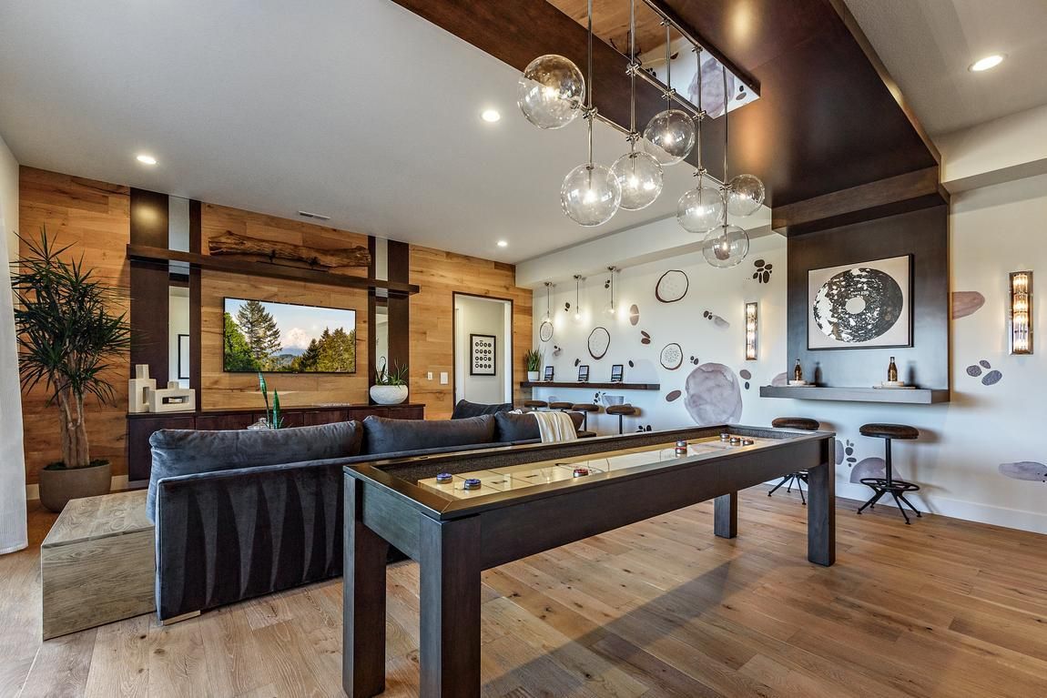 Game room with shuffleboard, TV, bar, and seating; light wood floor.