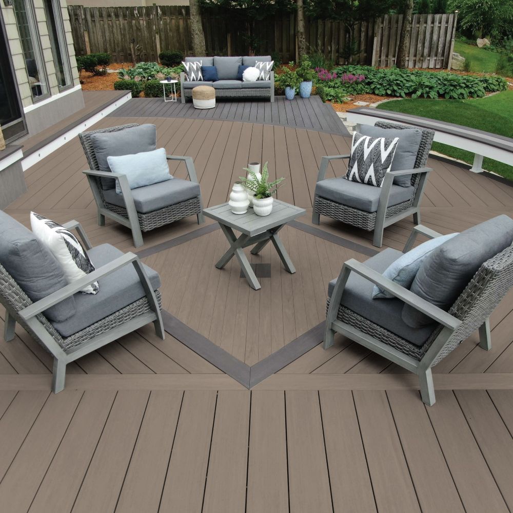 Outdoor deck with gray furniture: sofa, armchairs, and a small table. Brown decking, green grass.