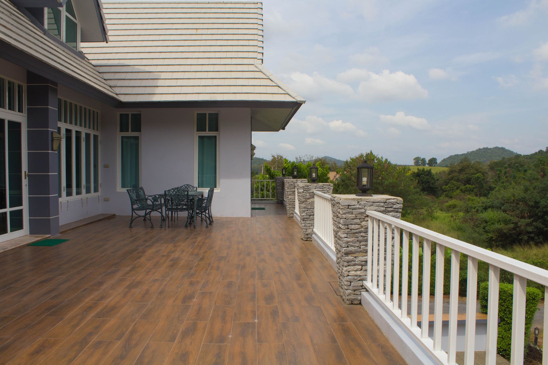 A house with a large wooden deck overlooking a green landscape and distant hills.