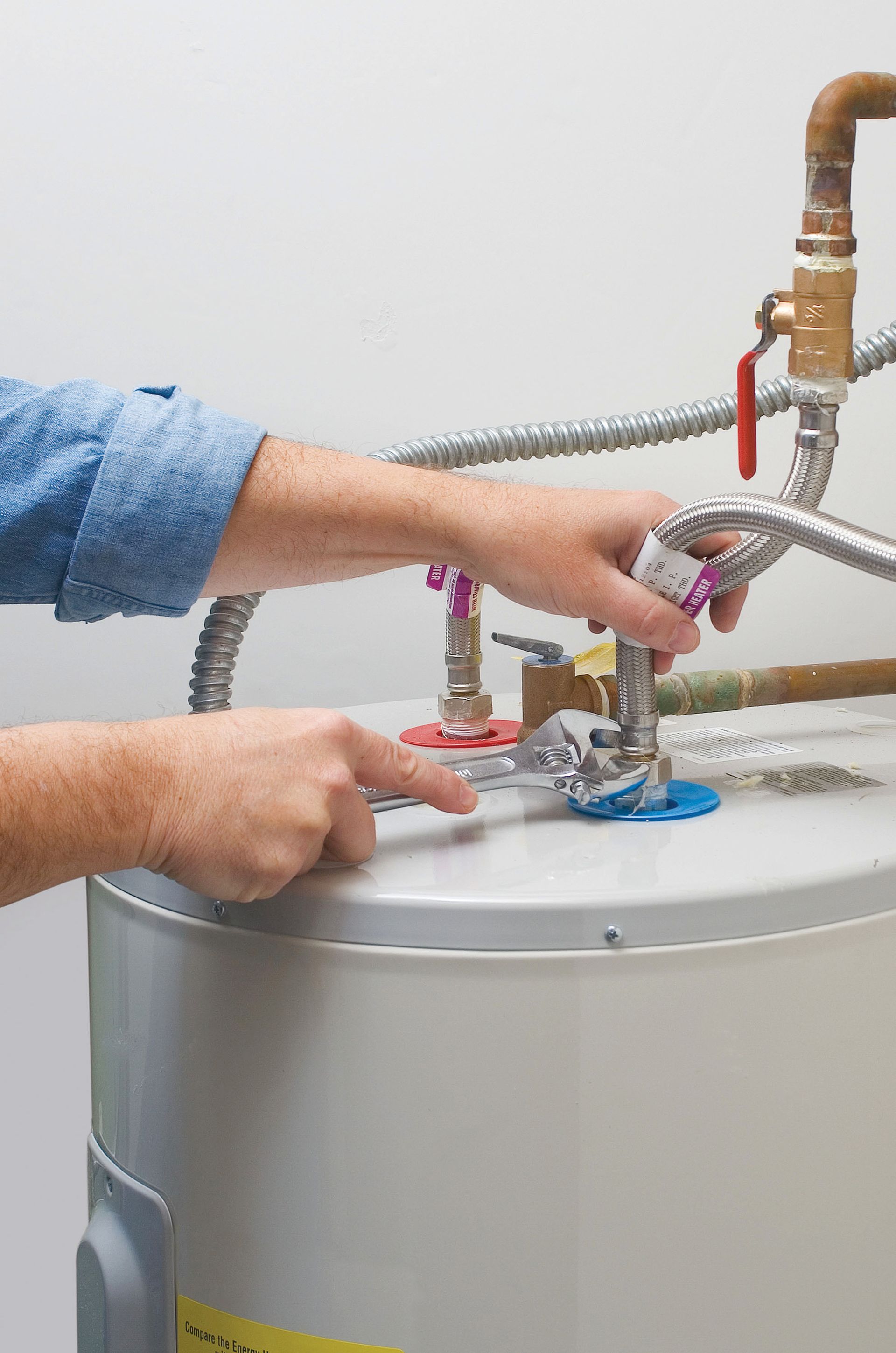 plumber inspecting water heater with pressure gauge and tools