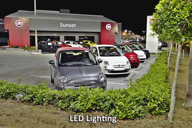 A row of cars are parked in front of a sunset car dealership
