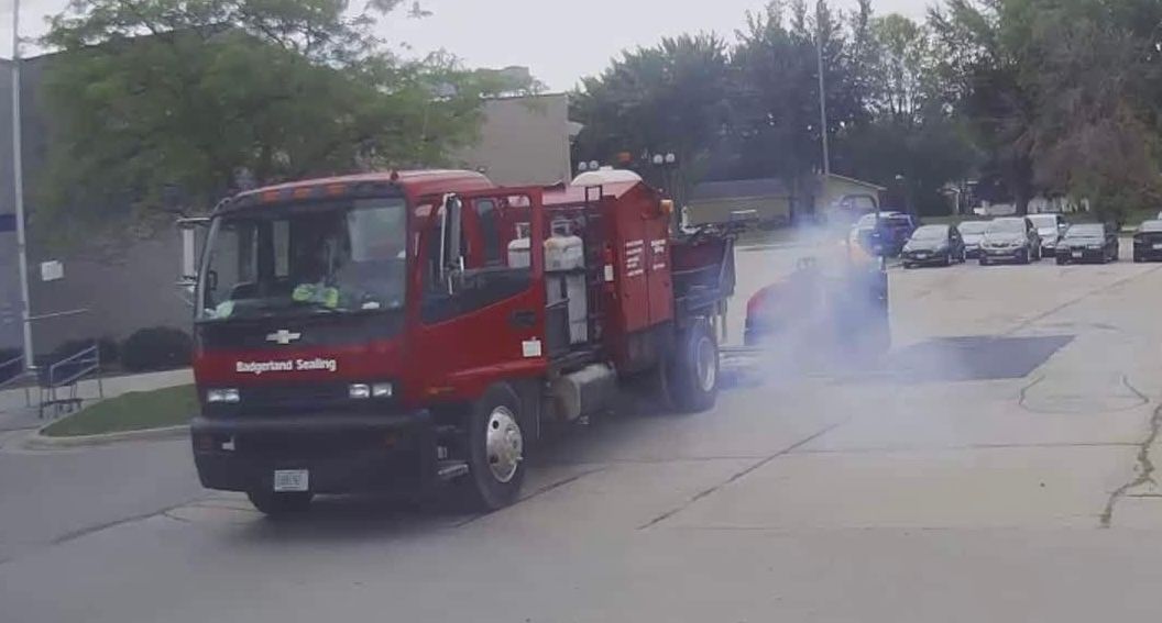 Red truck emitting smoke from a hatch. Outdoor setting, parked.