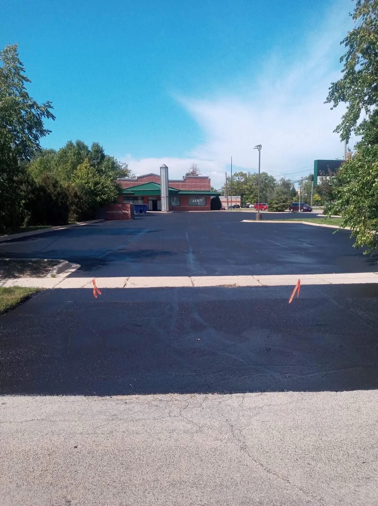 Newly paved parking lot with a building in the background under a blue sky.