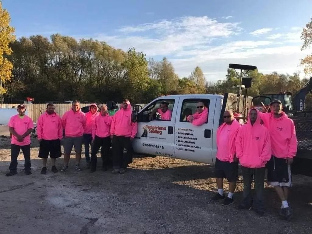 A group of people wearing pink hoodies stands by a white truck with logo 