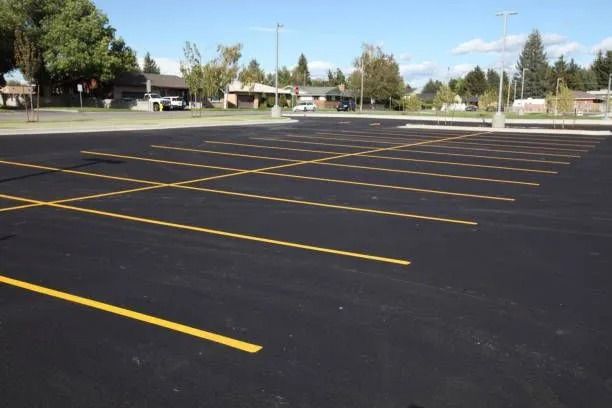 Empty asphalt parking lot with yellow painted parking space lines.