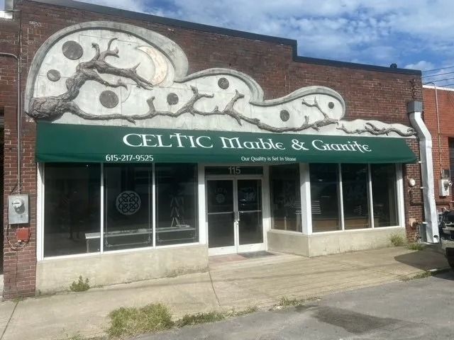 The brick storefront of Celtic Marble & Granite, featuring a distinctive decorative carved façade above a green awning.