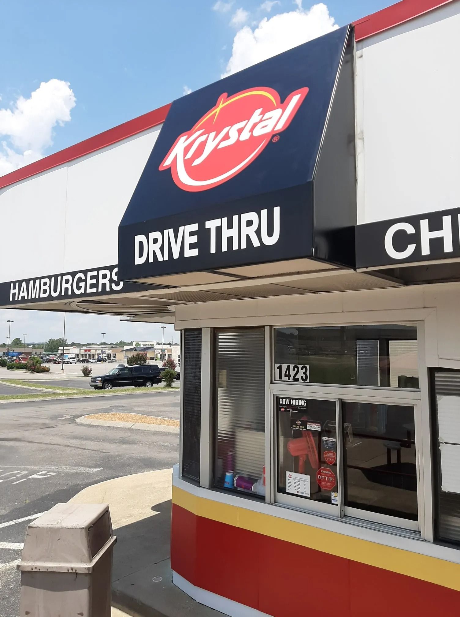 A Krystal fast food restaurant drive-thru window with a black awning and red and yellow exterior paint.