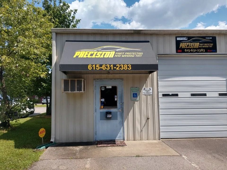 A Precision Auto Styling business office entrance with a black awning displaying the business name and phone number.