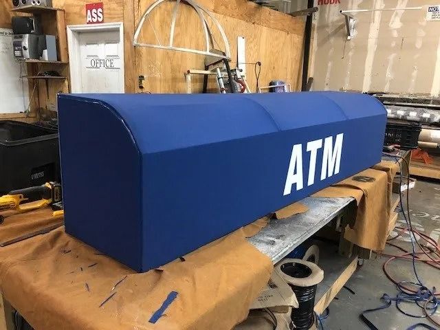 A blue fabric ATM canopy cover sits on a workbench in a workshop.