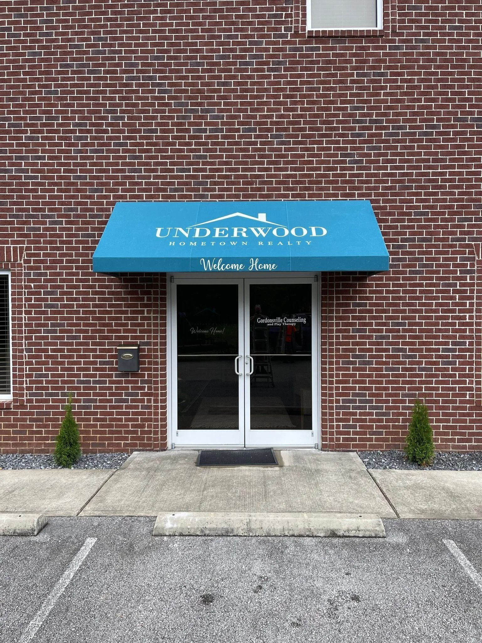 A brick building entrance with a blue awning labeled 