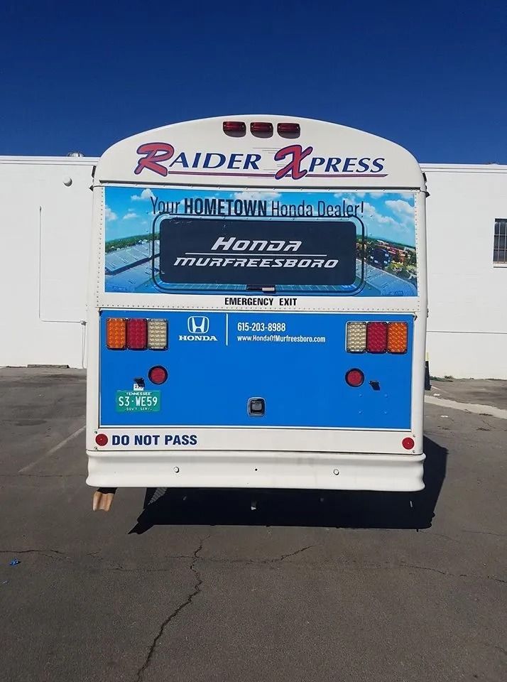 Rear view of a Raider Xpress bus featuring advertisements for Honda of Murfreesboro against a blue and white background.