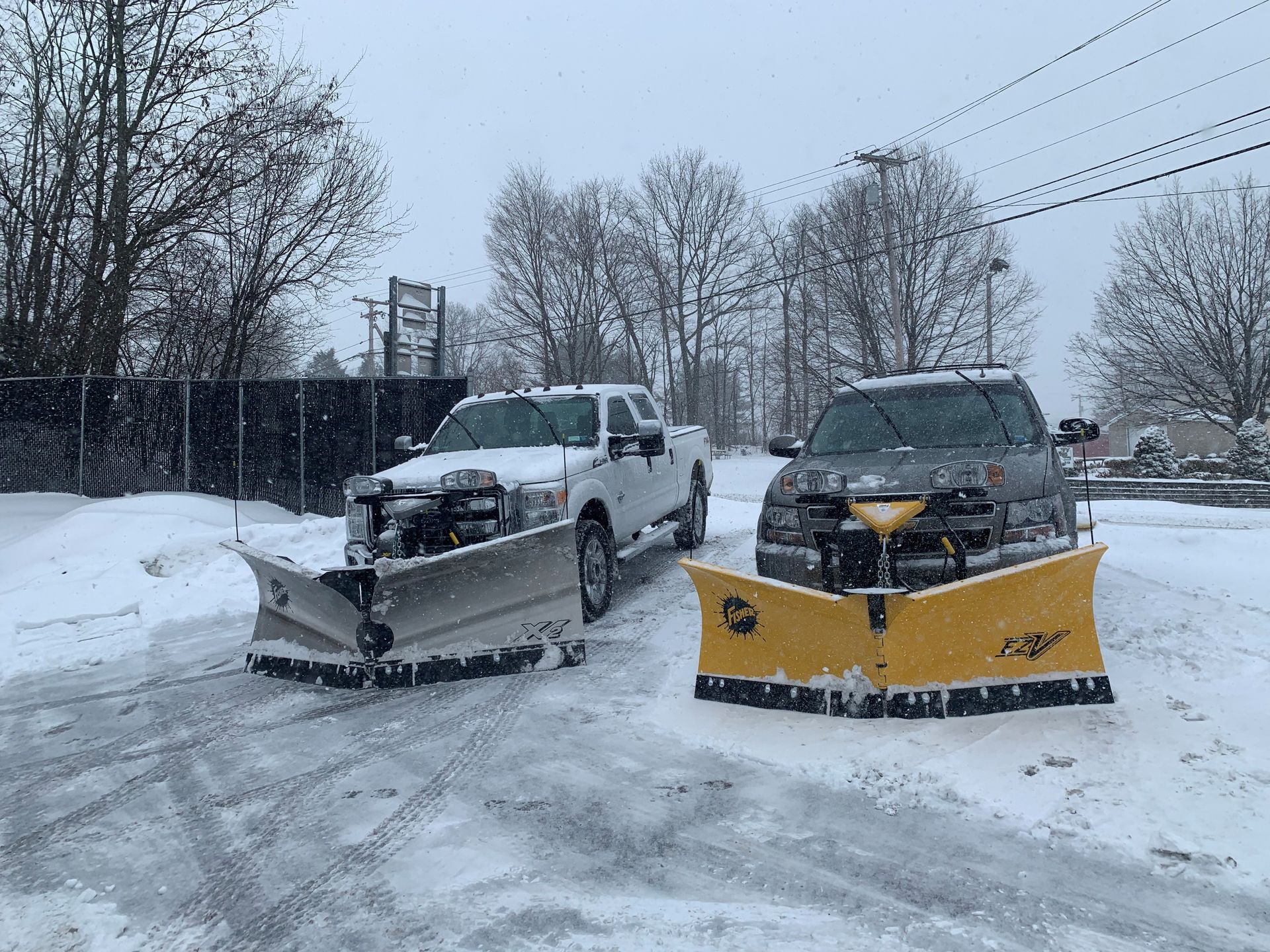 Two snow plows are parked next to each other in the snow.