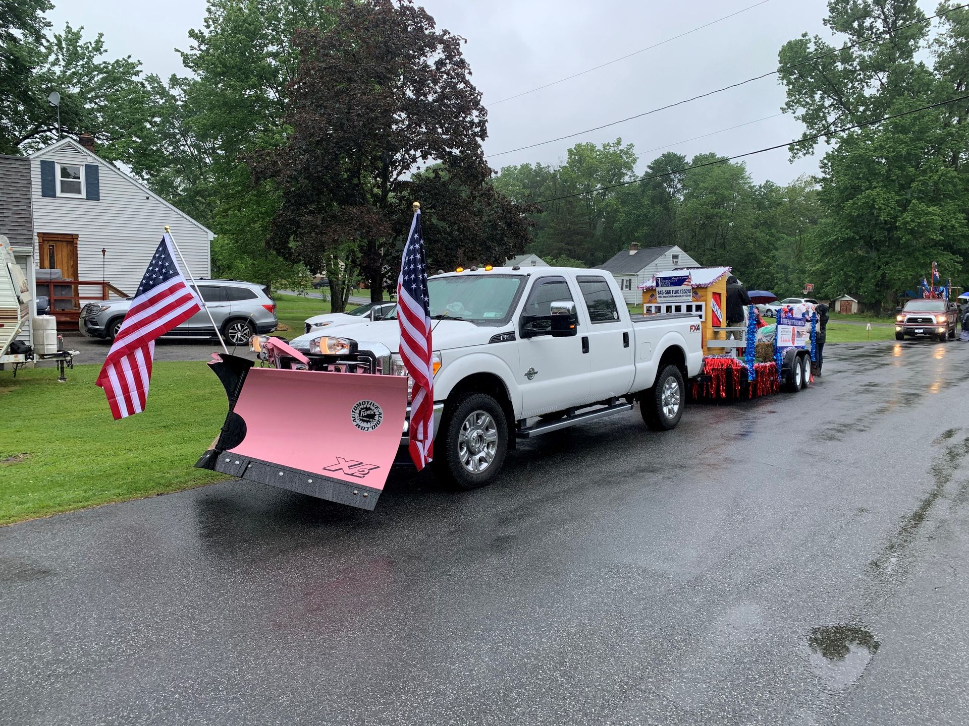A white truck with a snow plow attached to it is parked on the side of the road.