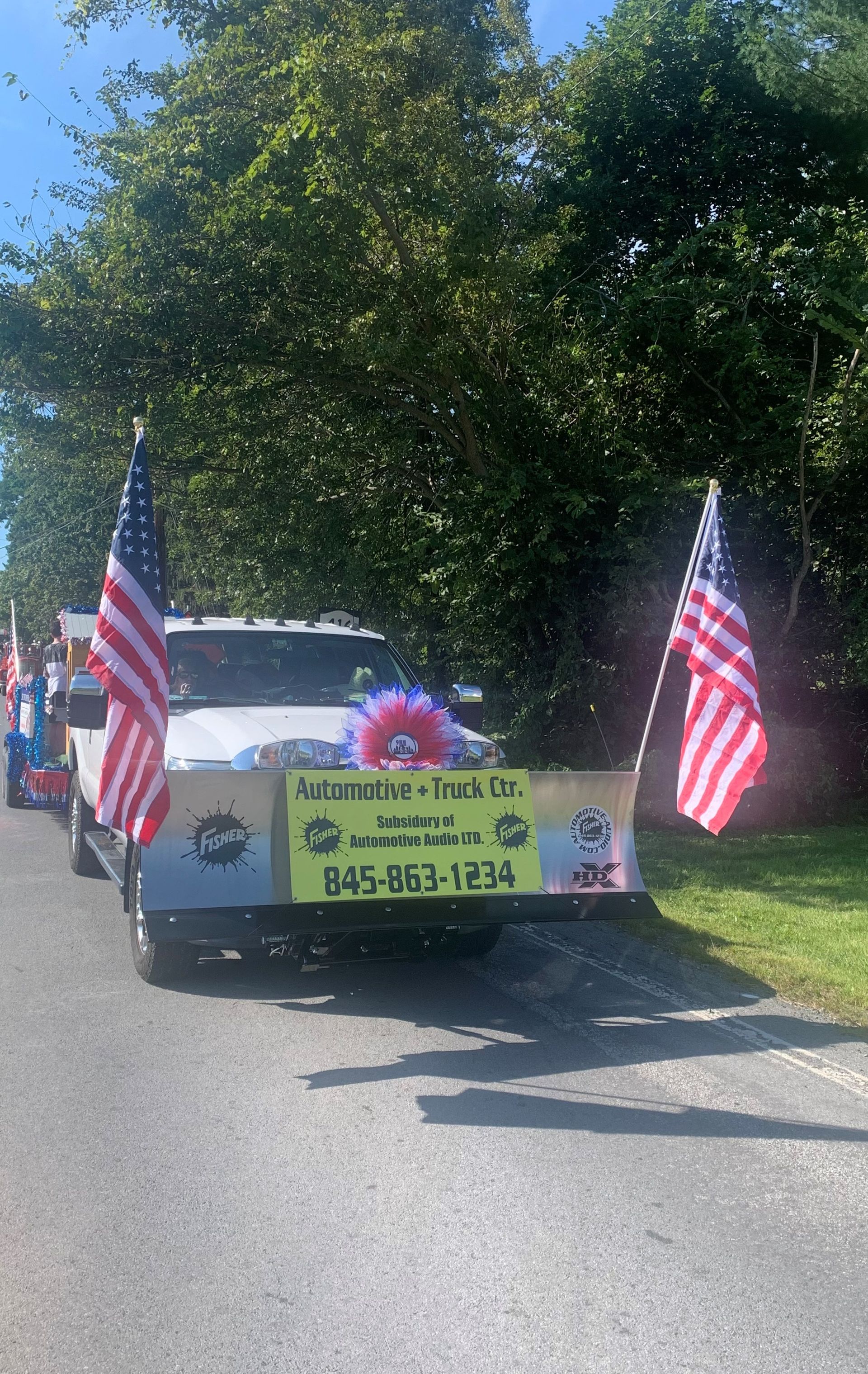 A white truck decorated with american flags is parked on the side of the road.