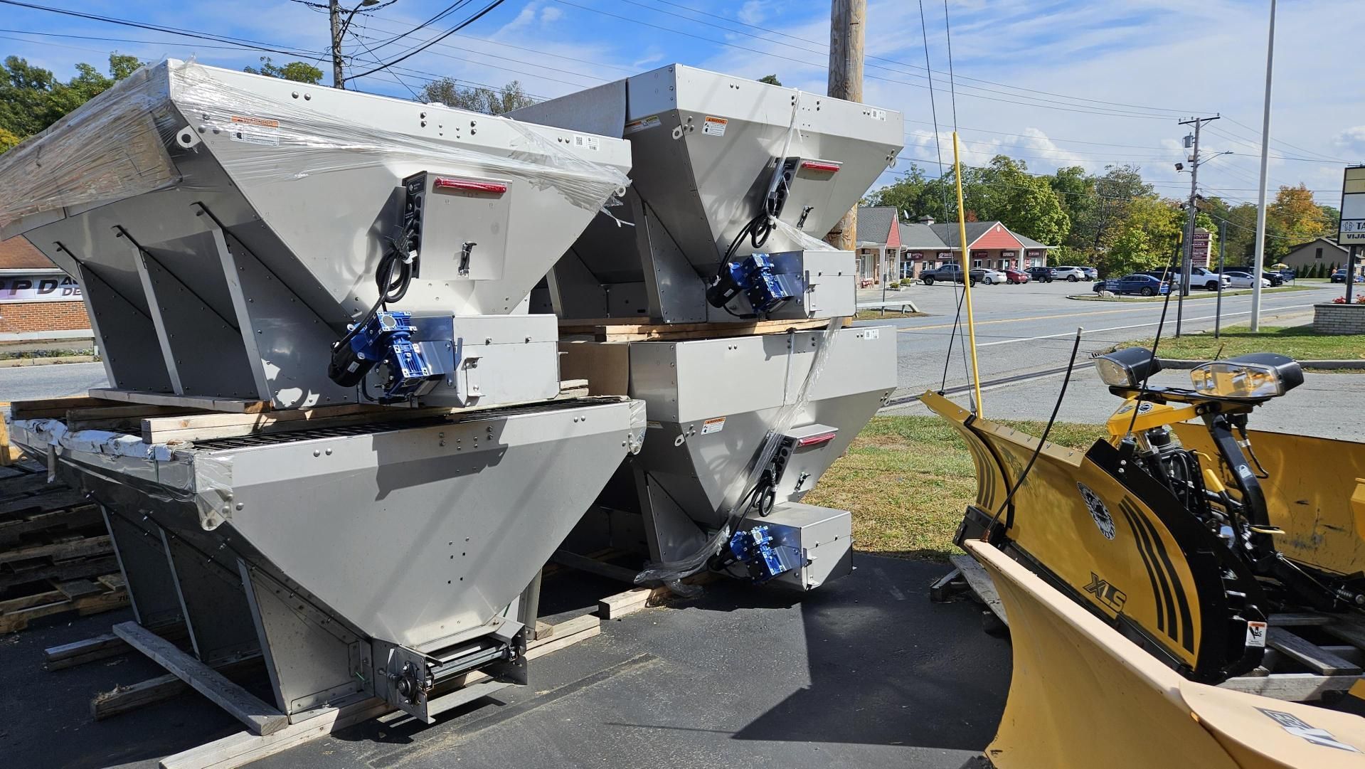Two snow plows are parked next to each other on the side of the road.