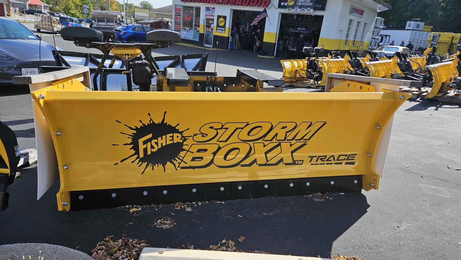 A yellow fisher box snow plow is parked in a parking lot