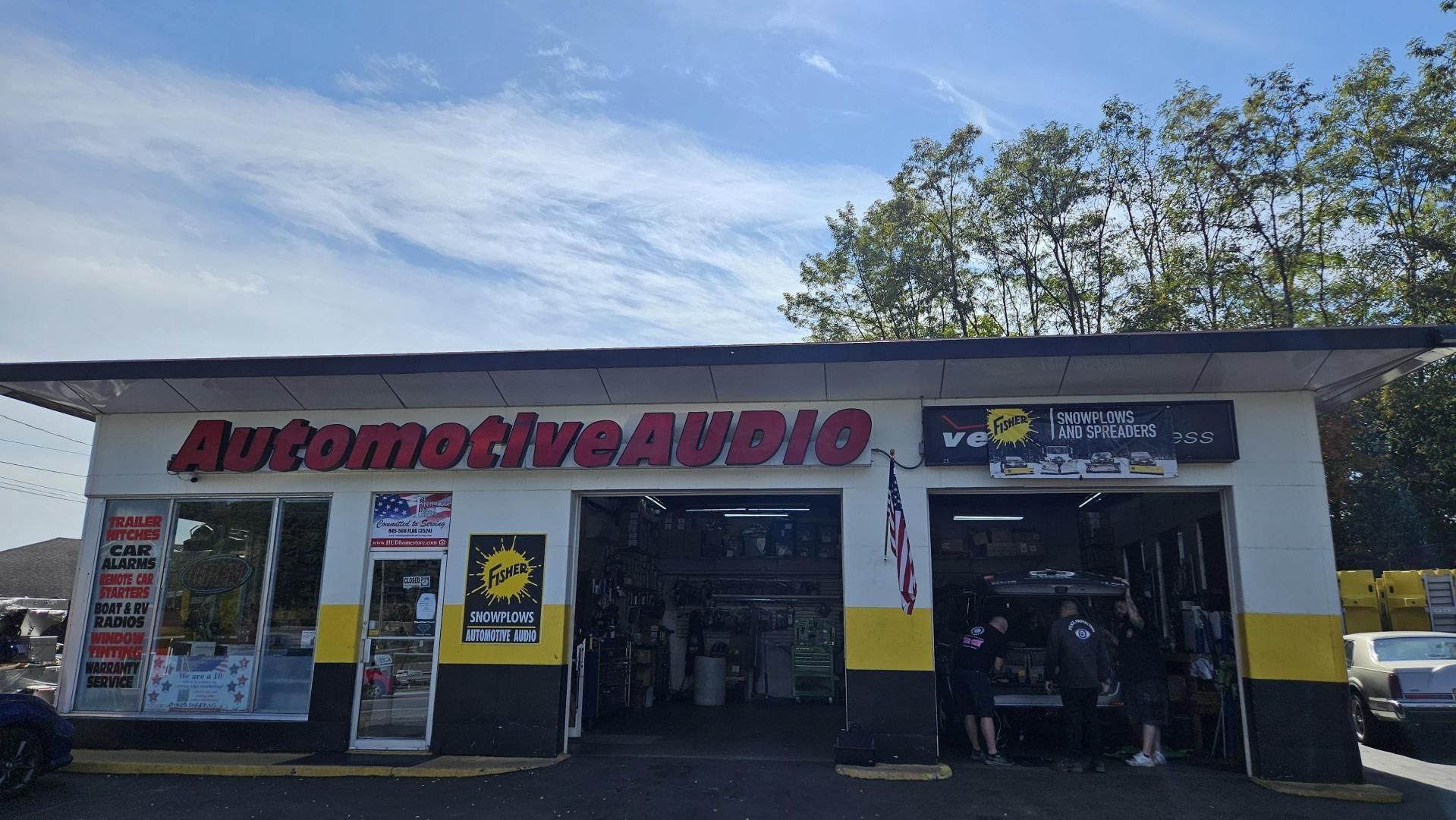 The front of an automotive audio store with cars parked in front of it.