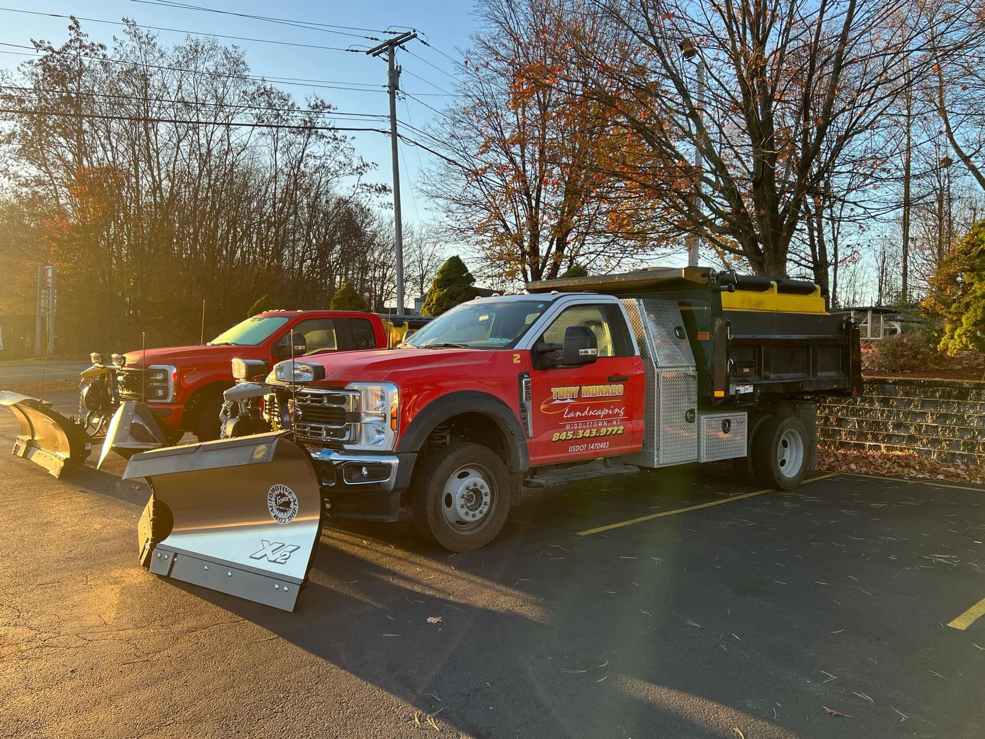 Two snow plows are parked next to each other in a parking lot.