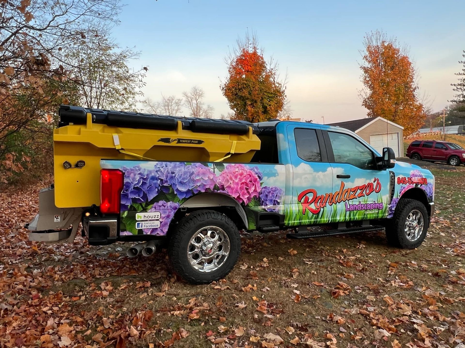 A truck with flowers painted on it is parked in a field.