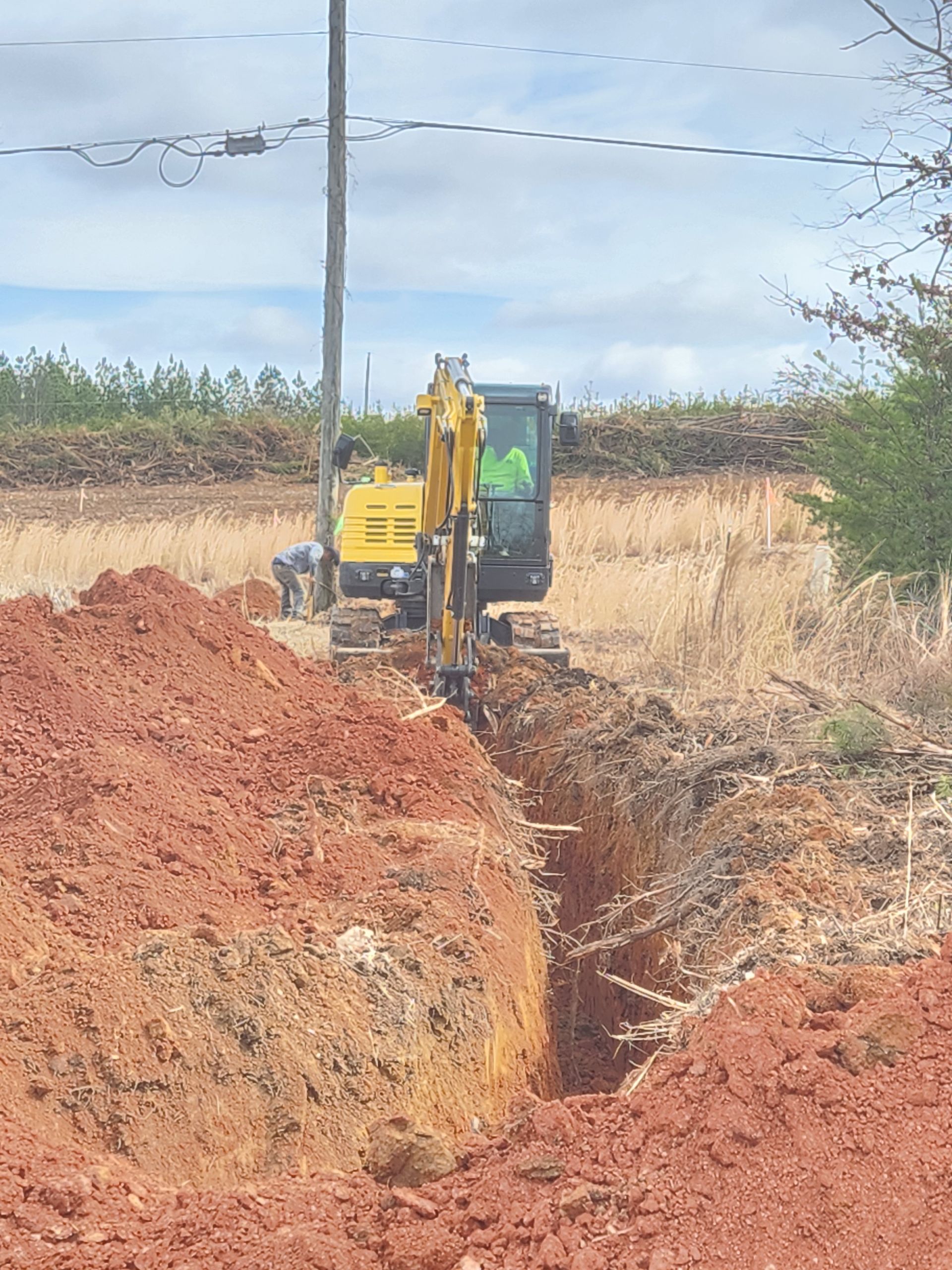 A yellow excavator is digging a hole in the dirt.