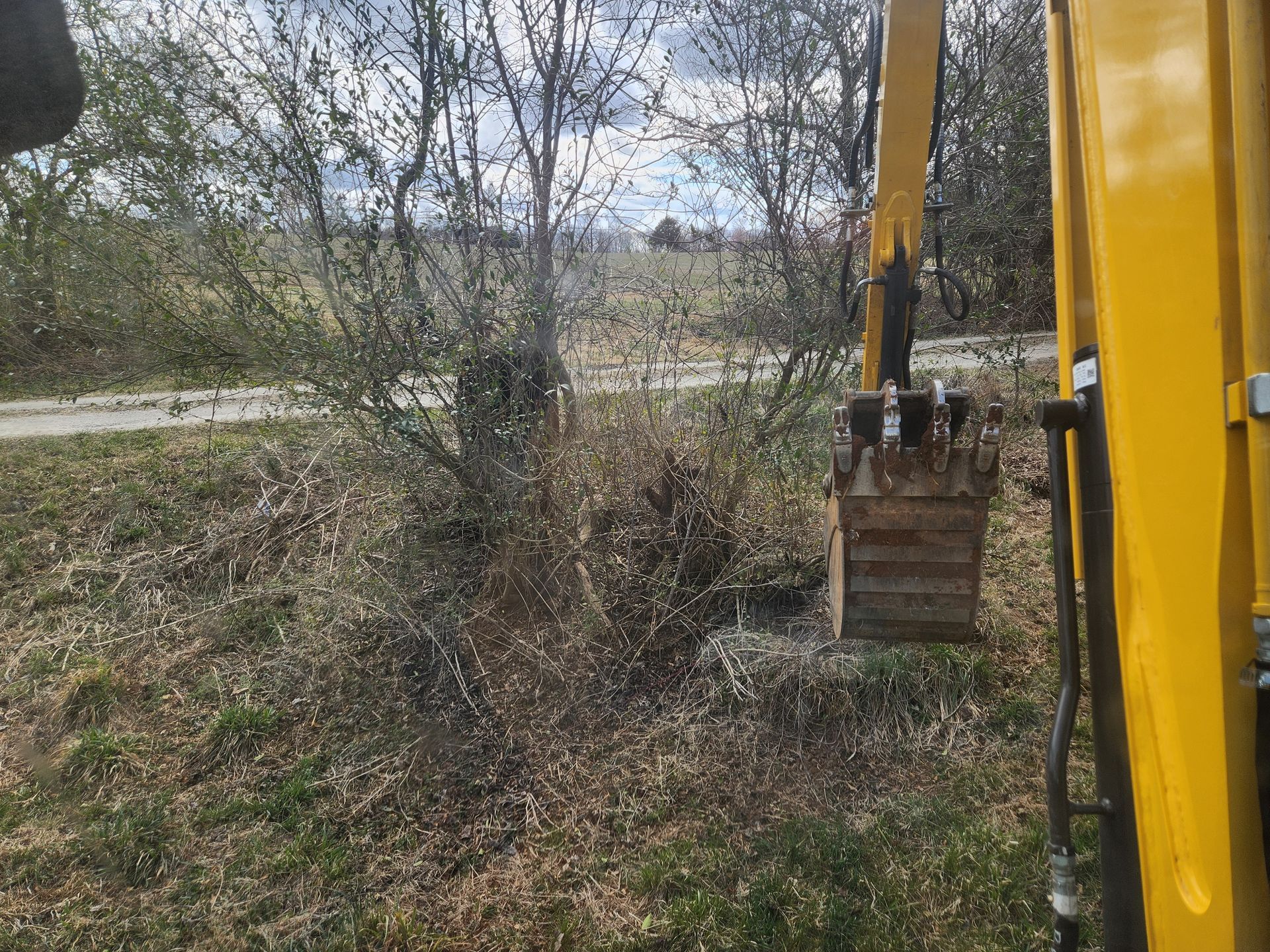 A yellow excavator is sitting in the middle of a field.