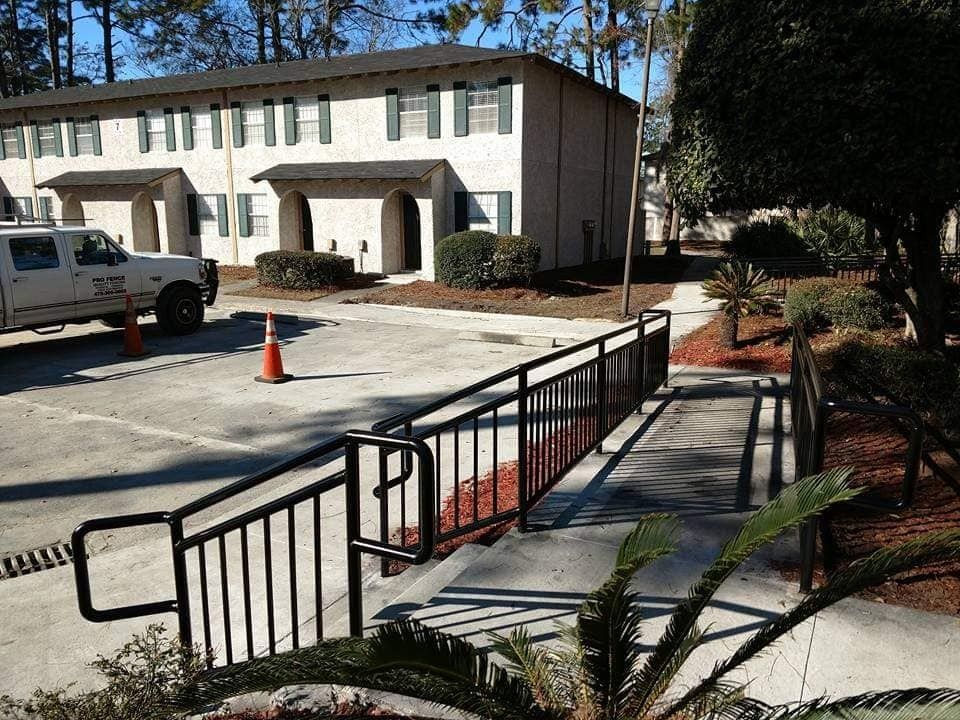 Accessible ramp and steps leading to a two-story beige building with a parked utility truck nearby.