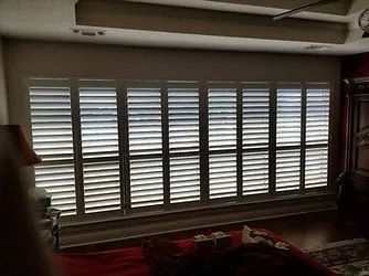 Large window with white plantation shutters in a dim living room