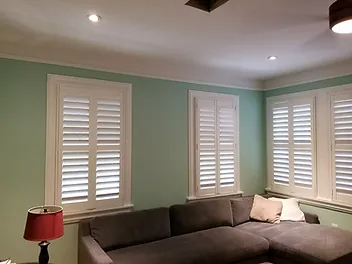 Corner living room with mint walls, white shutters, a gray sectional sofa, and a red floor lamp.