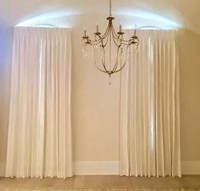 White curtains framing a chandelier in a softly lit room