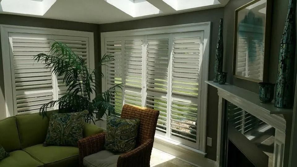 Bright living room with green chairs, a potted plant, large windows, and a fireplace
