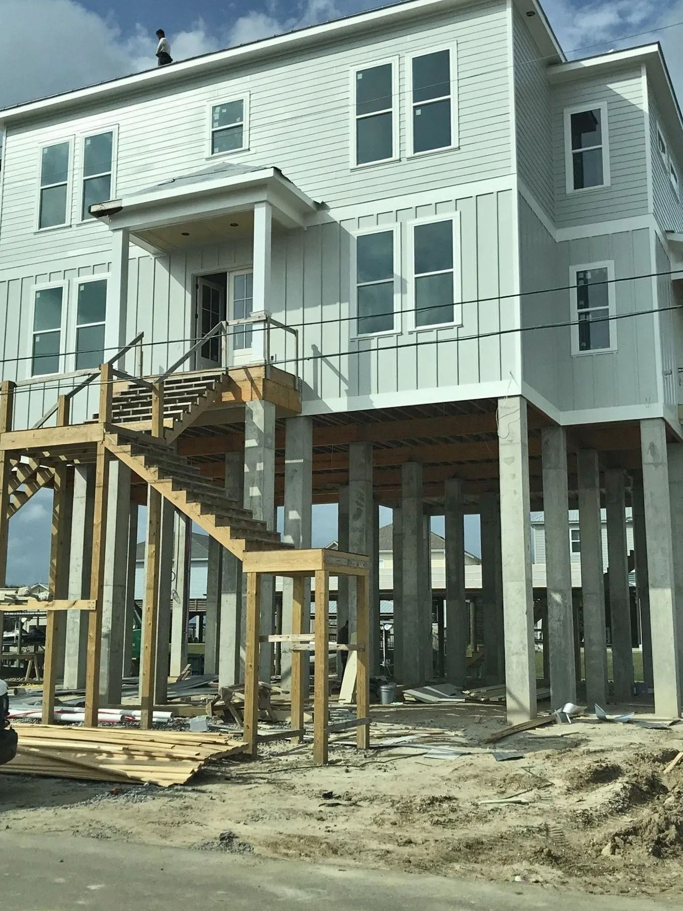 Raised beach house under construction with a front staircase and wooden support posts