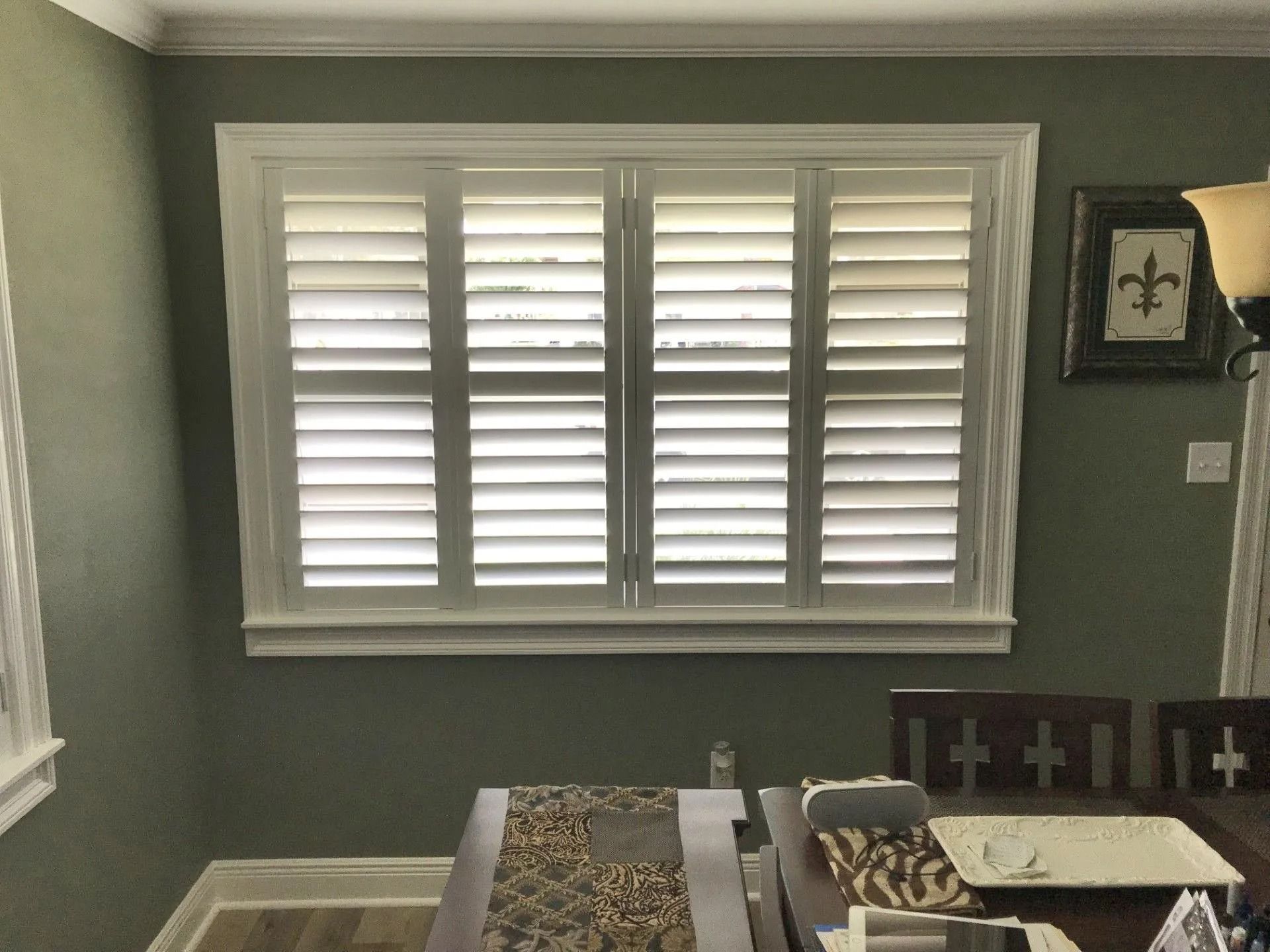 Bedroom with a bed, window shutters, and wall art in muted gray-green tones
