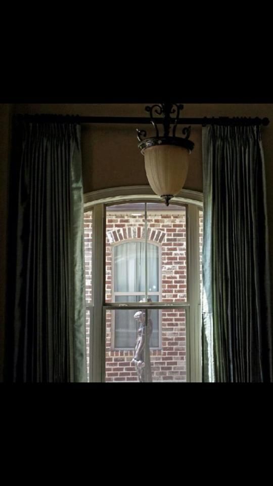 Dim room with curtains framing a window view of a brick building and window