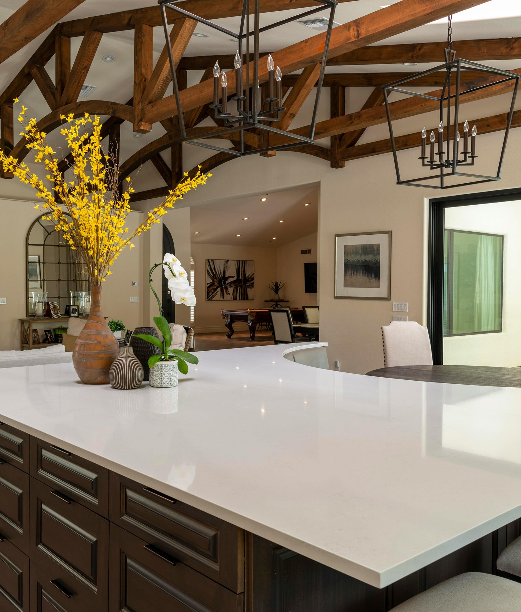 Kitchen with white countertop island, dark brown cabinets, and yellow floral arrangement.