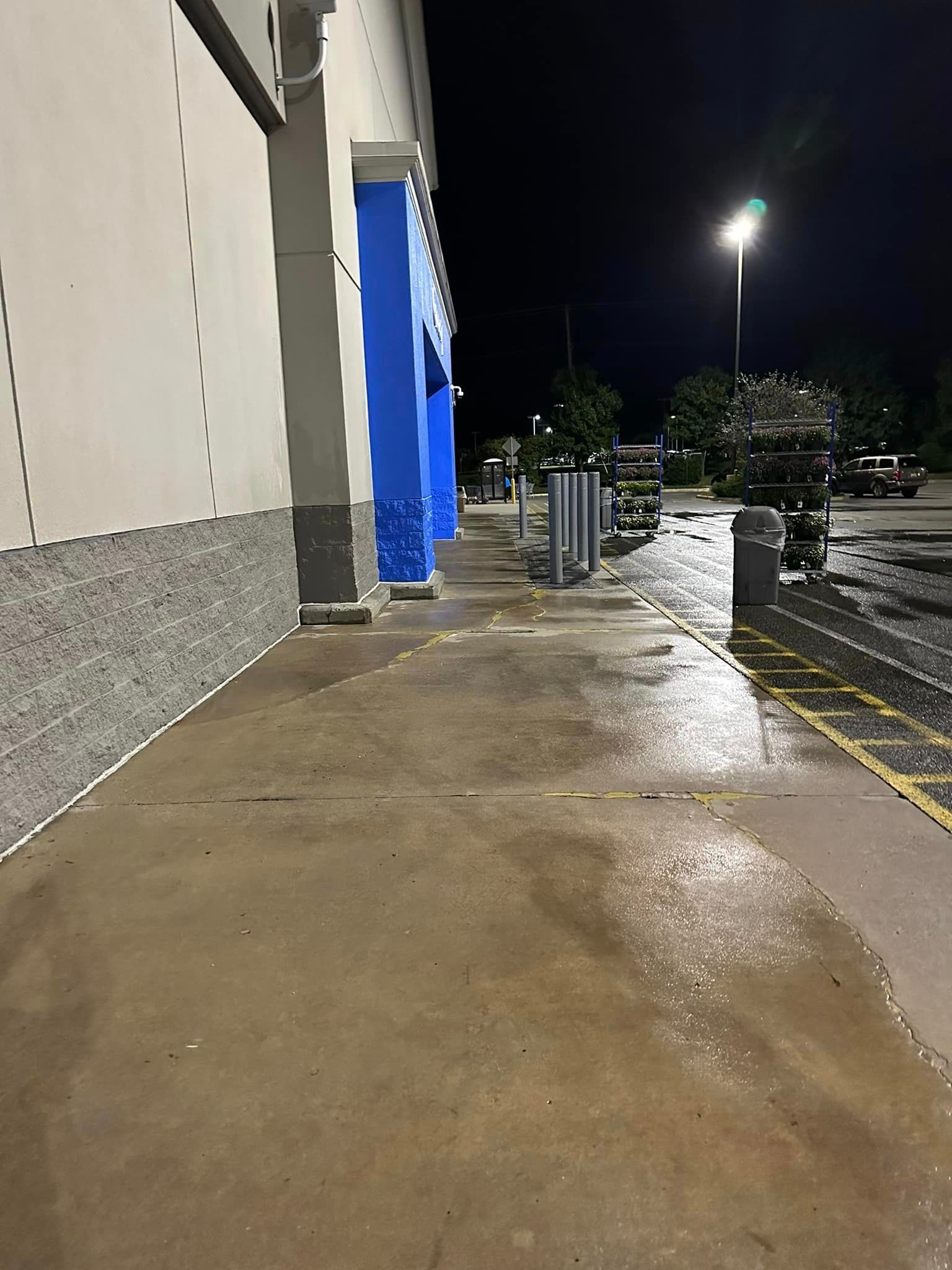 A wet sidewalk in front of a building at night.