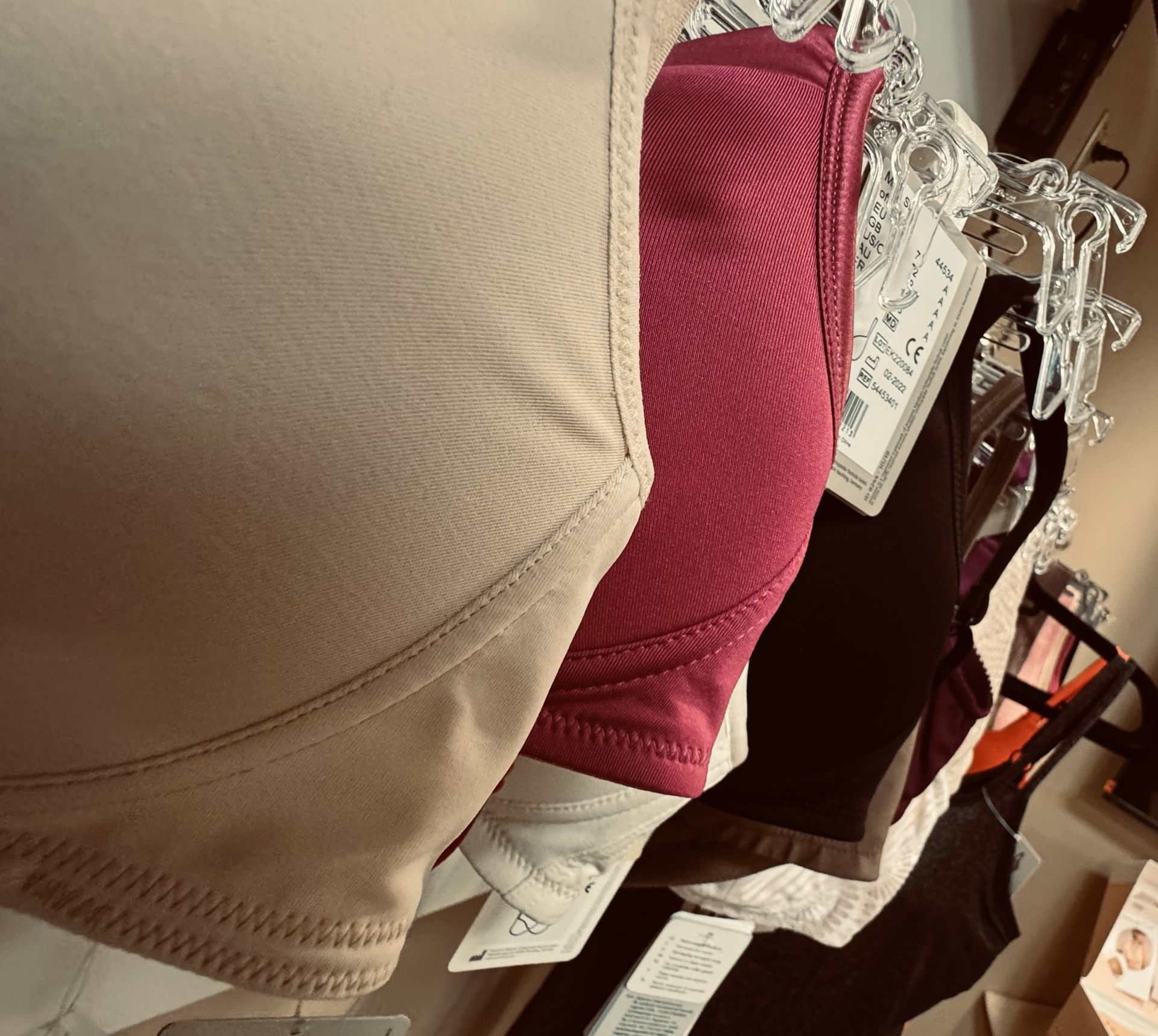 A row of different colored bras are hanging on a rack