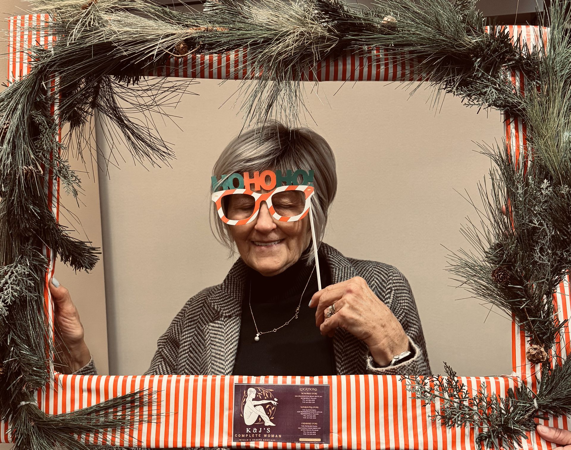 A woman wearing glasses is standing in a picture frame.
