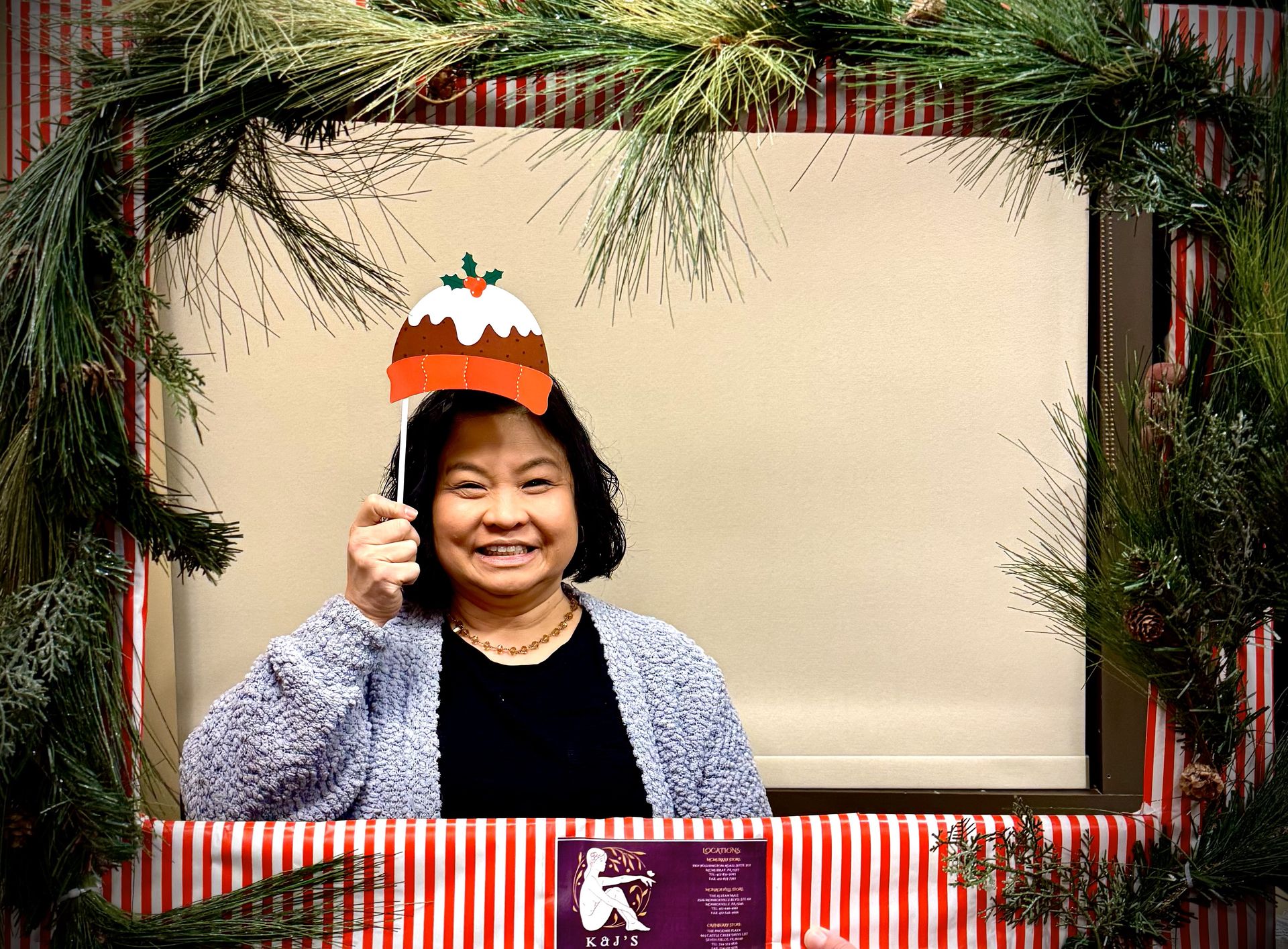 A woman is holding a pudding hat in front of a christmas frame.