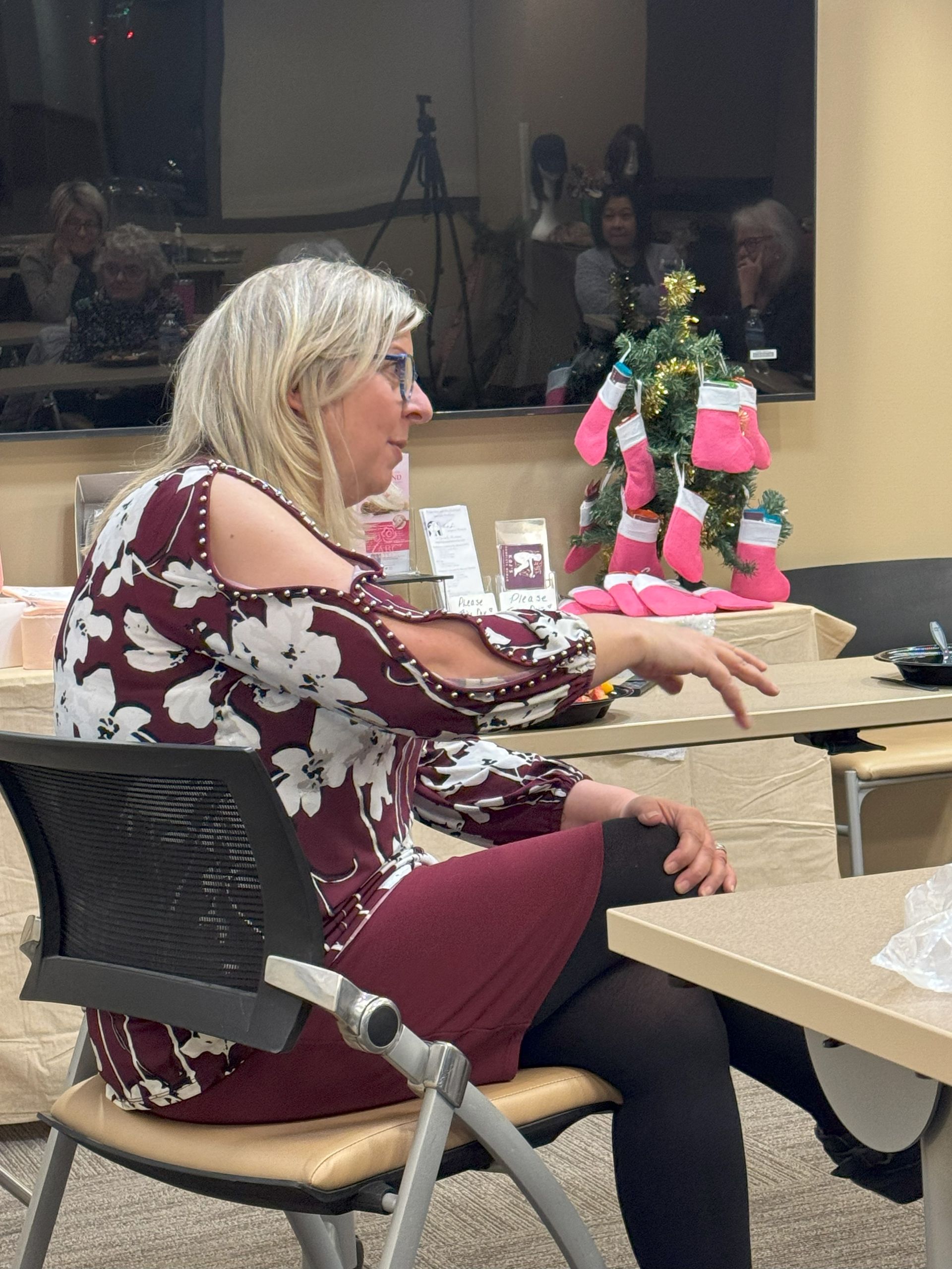 A woman is sitting in a chair in front of a christmas tree.