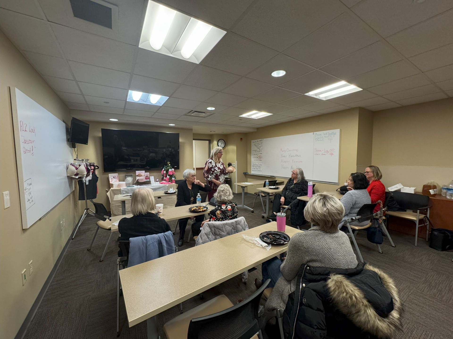 A group of people are sitting at tables in a classroom.