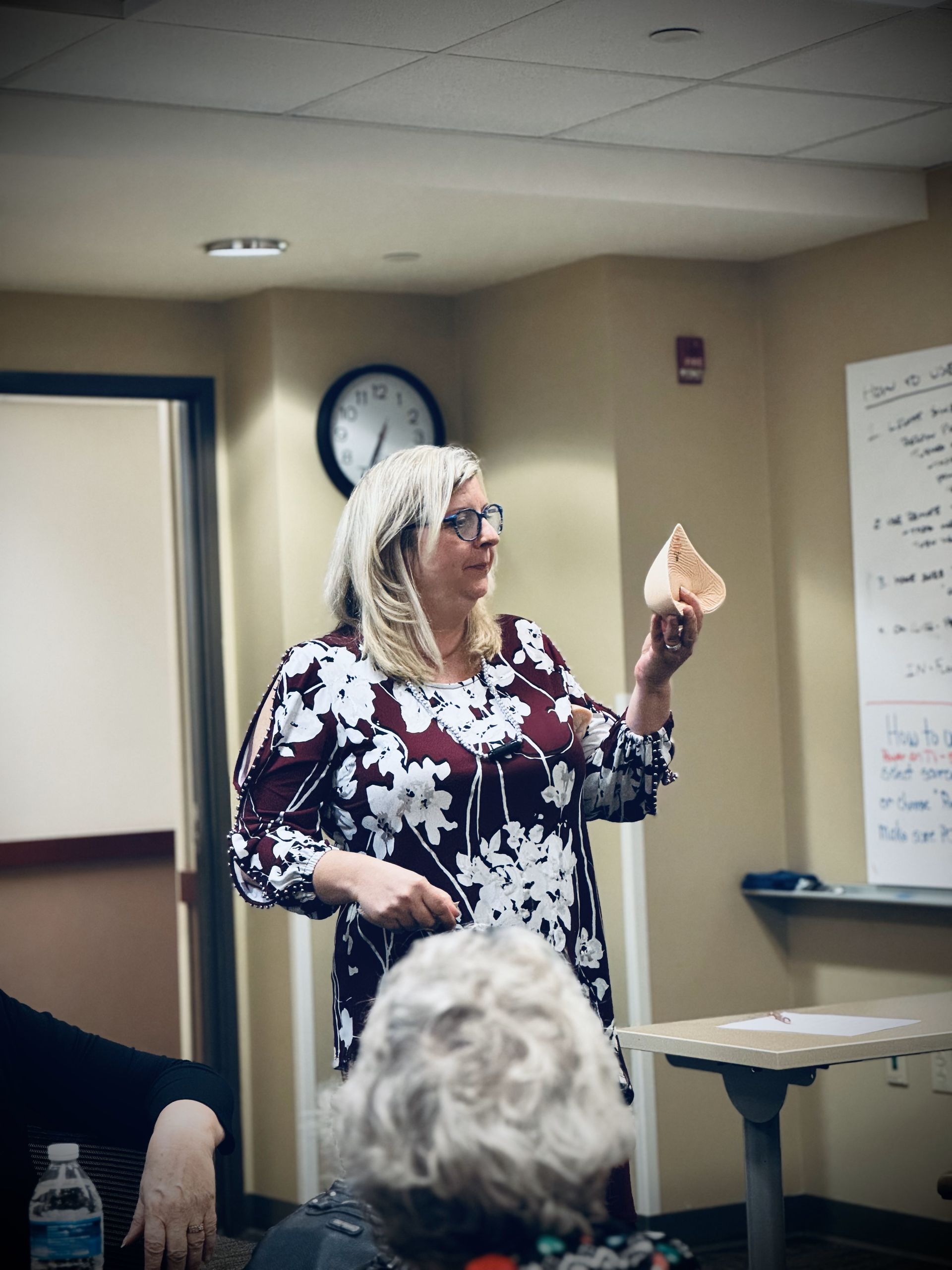 A woman in a floral shirt is giving a presentation