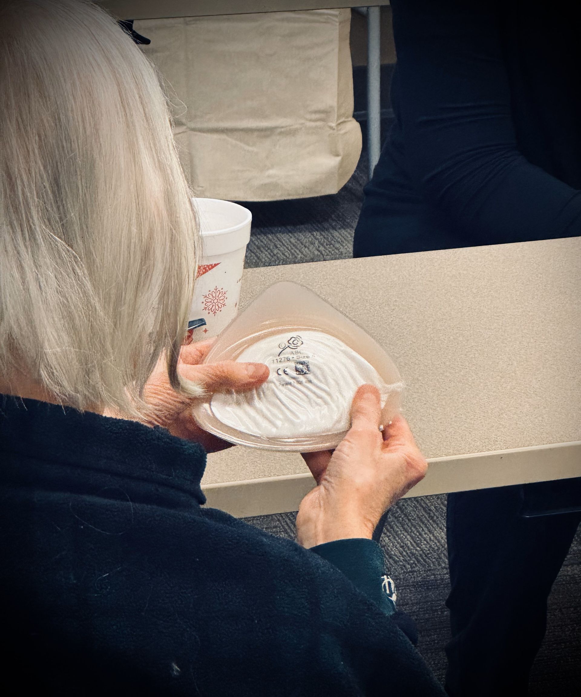 A woman is sitting at a table holding a plate of food.