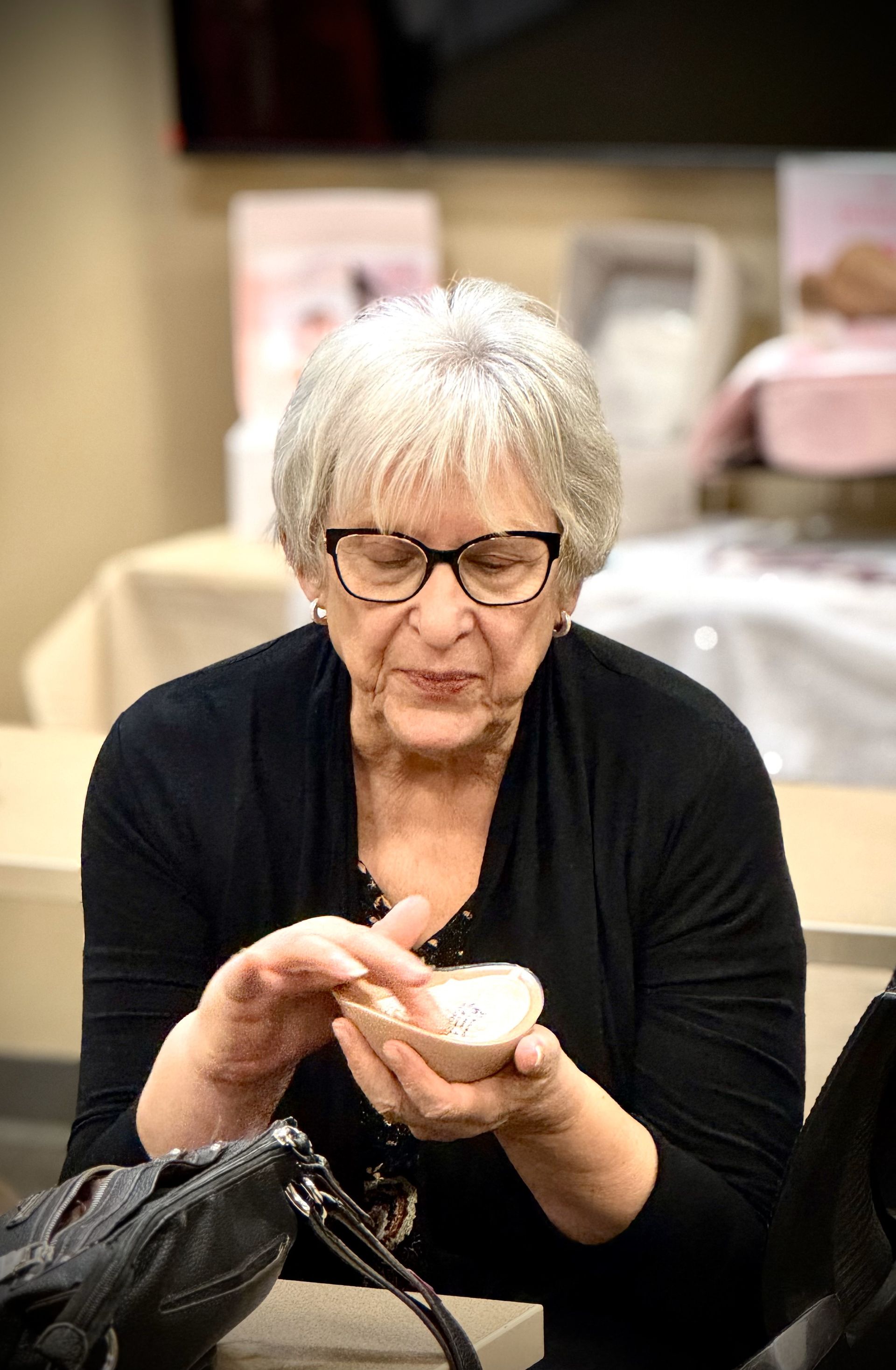 A woman wearing glasses is holding a piece of bread in her hands.