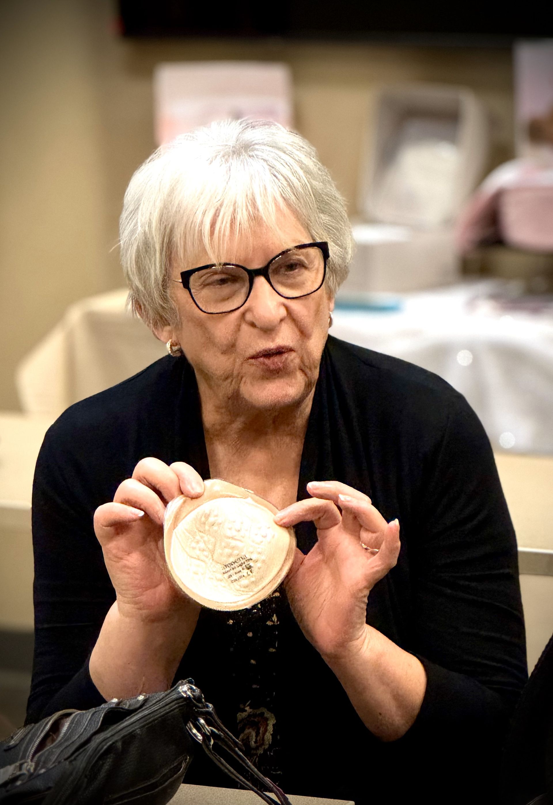 A woman wearing glasses is holding a piece of wood in her hands.