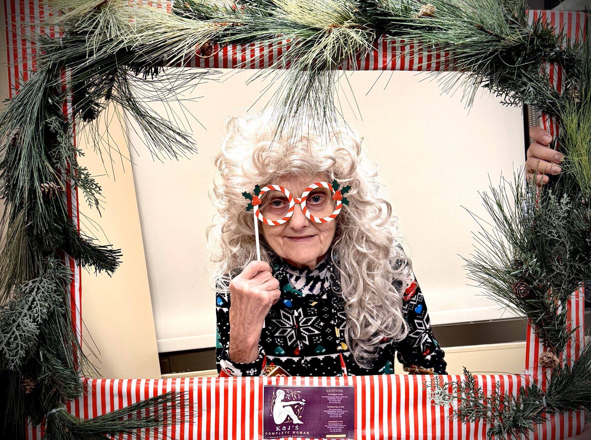 An elderly woman is posing for a picture in a christmas frame.