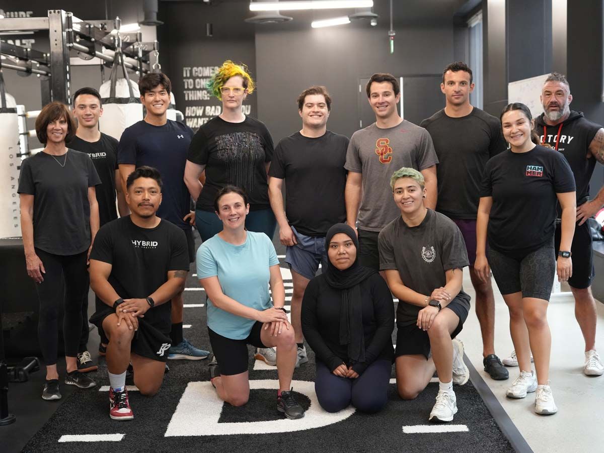 A group of people are posing for a picture in a gym.