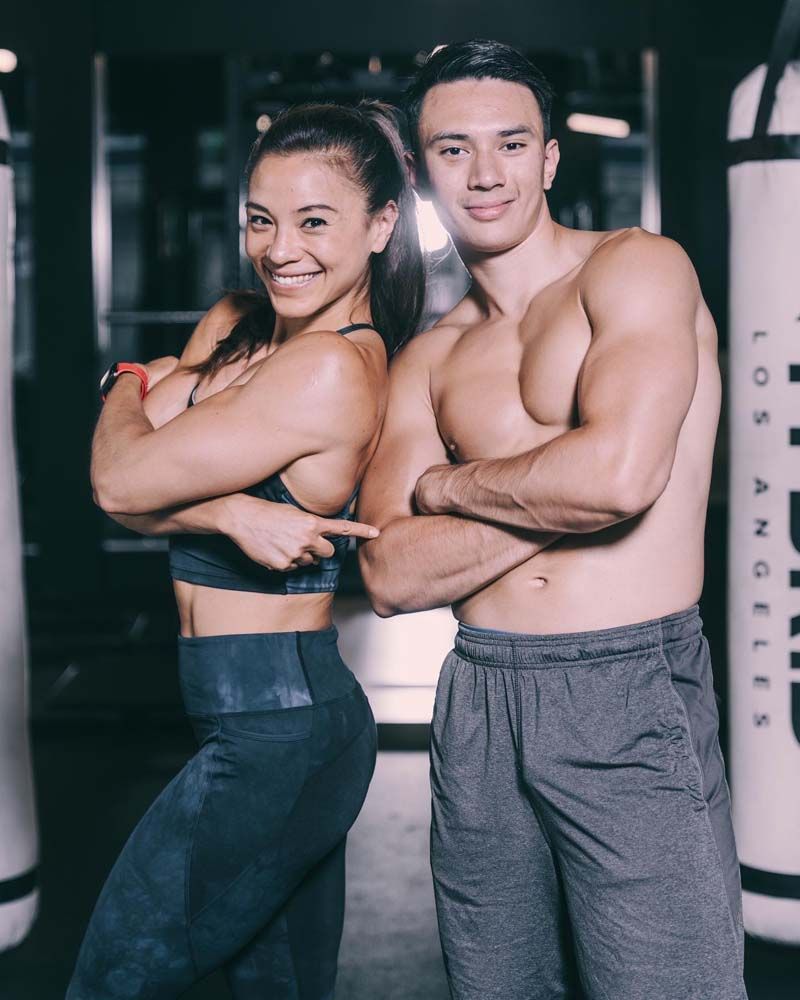 A man and a woman are posing for a picture in a gym.