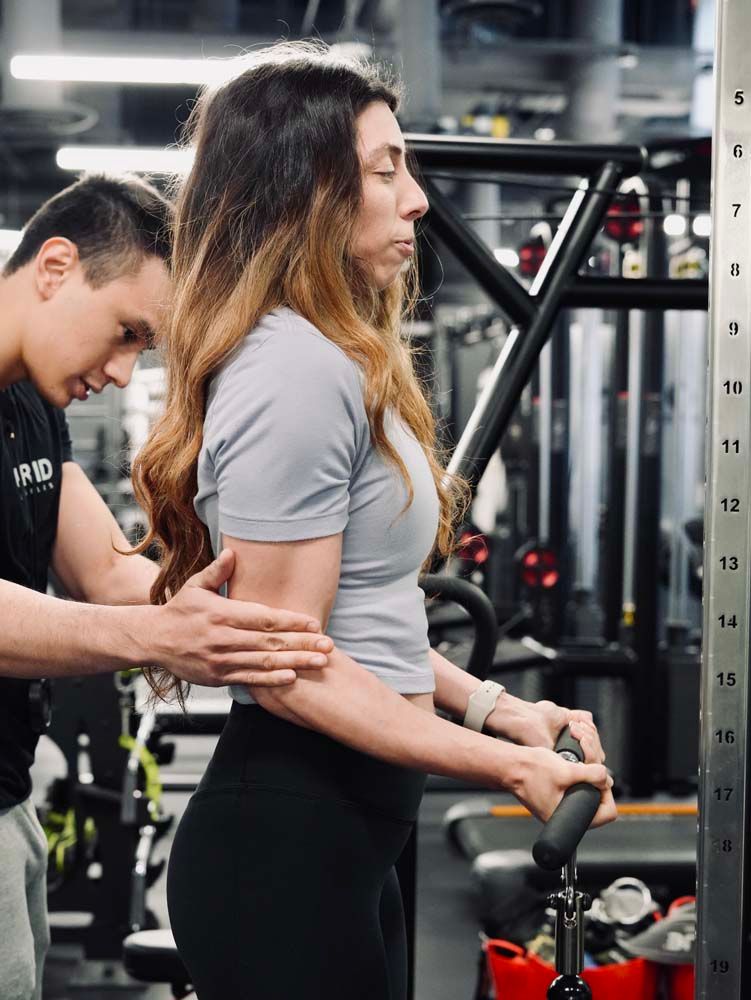 A man is helping a woman do exercises in a gym.