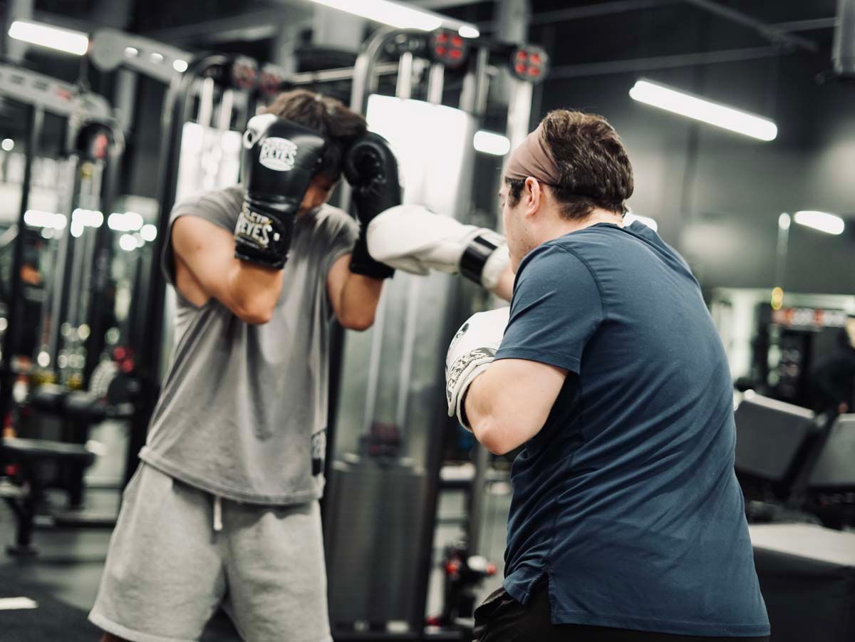Two men are boxing in a gym and one of them is wearing everlast gloves.