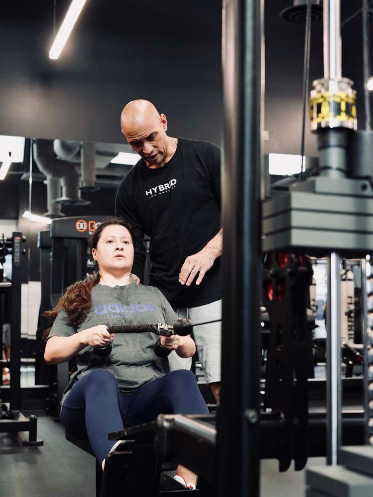 A man is teaching a woman how to use a machine in a gym.